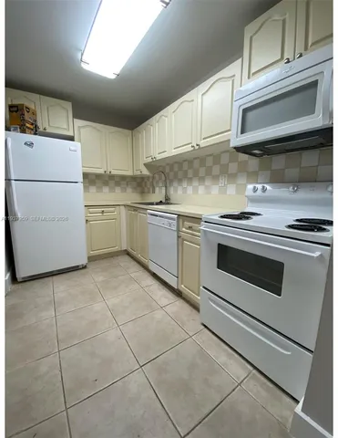 a kitchen with a stove white cabinets and white appliances
