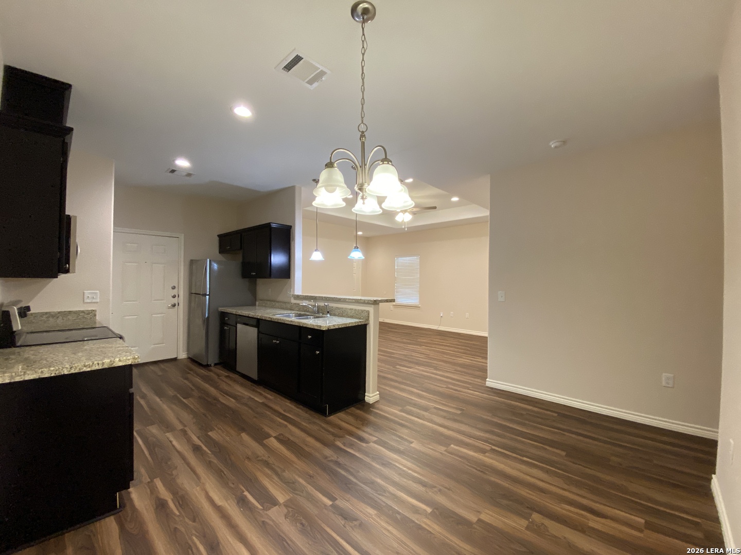 629 Commerce Street Pleasanton, TX 78064 - Photo 3 of 11 a large kitchen with stainless steel appliances granite countertop a stove and a wooden floor
