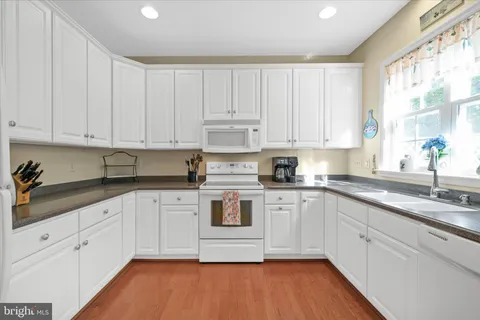 a kitchen with granite countertop white cabinets and white appliances