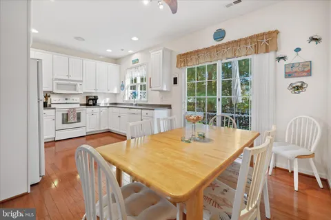a kitchen with stainless steel appliances granite countertop a stove a refrigerator a kitchen island a table and chairs