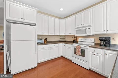 a kitchen with granite countertop white cabinets and refrigerator