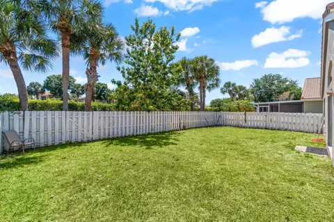 a view of backyard with green space and wooden fence