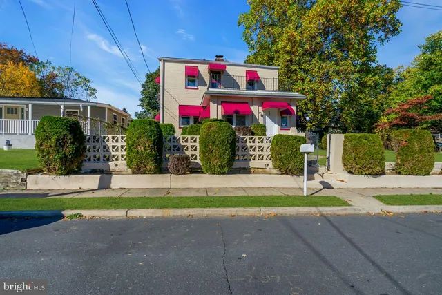 a front view of multi story residential apartment building with yard and sign board