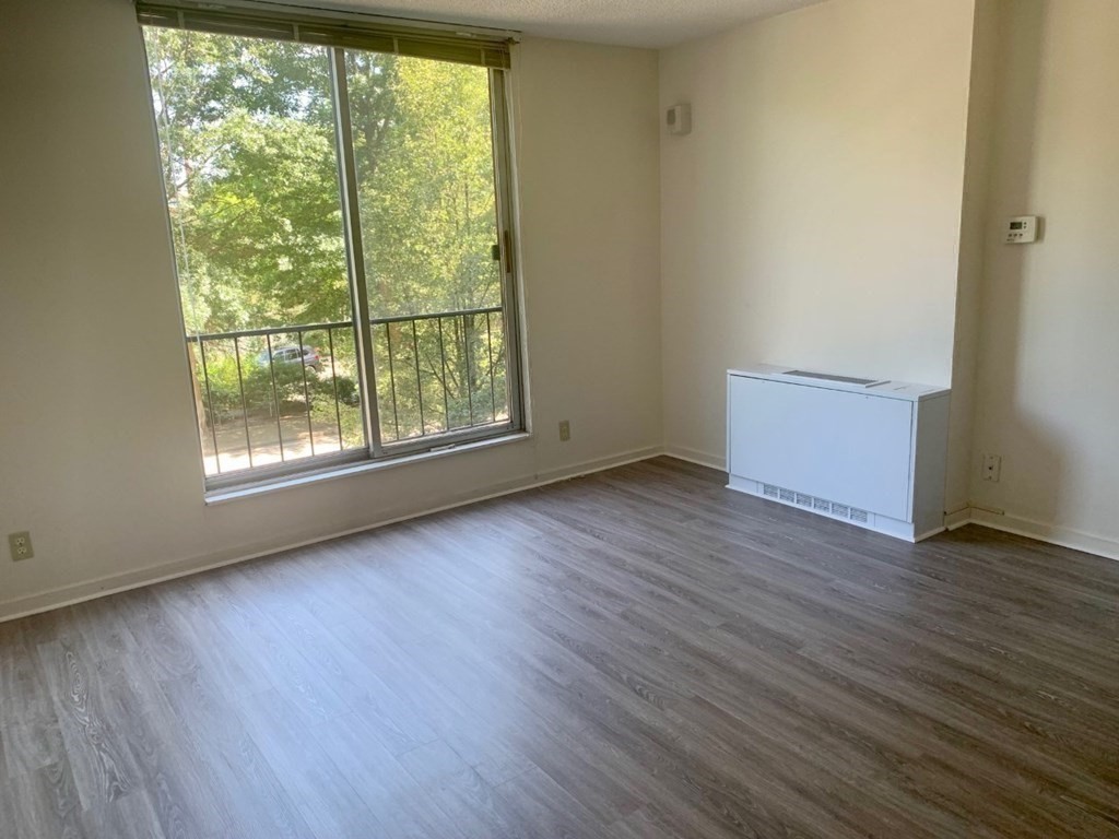 33 Pond Avenue, Unit 213 Brookline, MA 02445 - Photo 3 of 8 a view of an empty room with wooden floor and a window