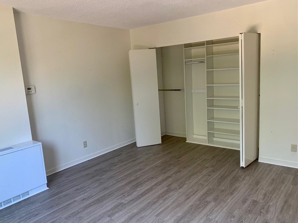33 Pond Avenue, Unit 213 Brookline, MA 02445 - Photo 5 of 8 an empty room with wooden floor and closet