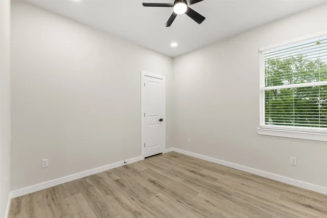 a view of an empty room with a window and wooden floor