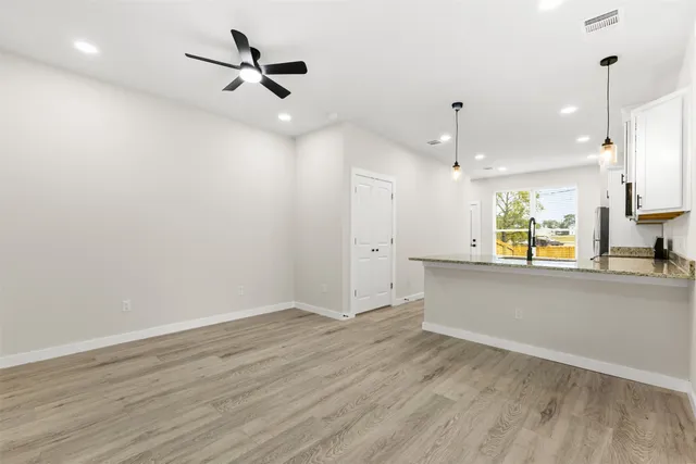 an empty room with wooden floor a ceiling fan and windows