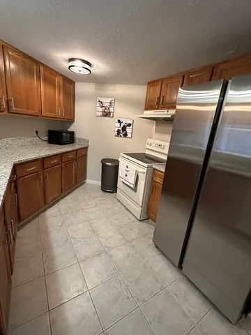 a kitchen with stainless steel appliances granite countertop a refrigerator and a stove top oven