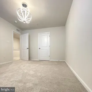 a view of an empty room and a chandelier fan