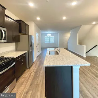 a kitchen with stainless steel appliances kitchen island granite countertop a refrigerator a stove and a sink with wooden floor