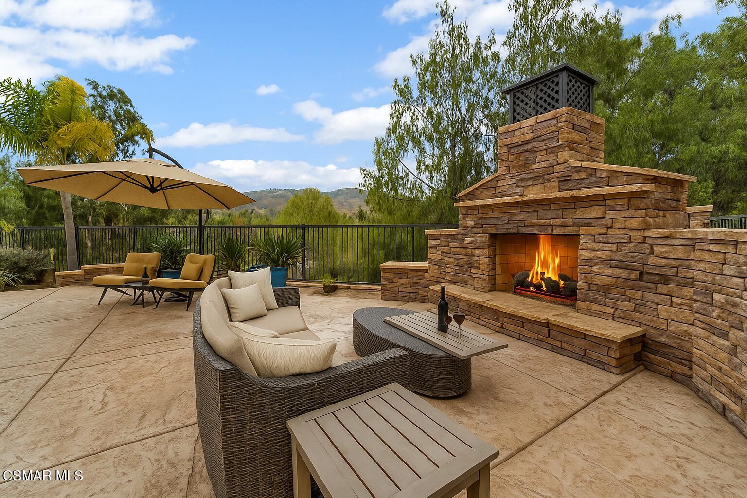 4101 Laurelview Drive Moorpark, CA 93021 - Photo 6 of 49 a view of a patio with couches table and chairs under an umbrella with a fire pit and wooden fence