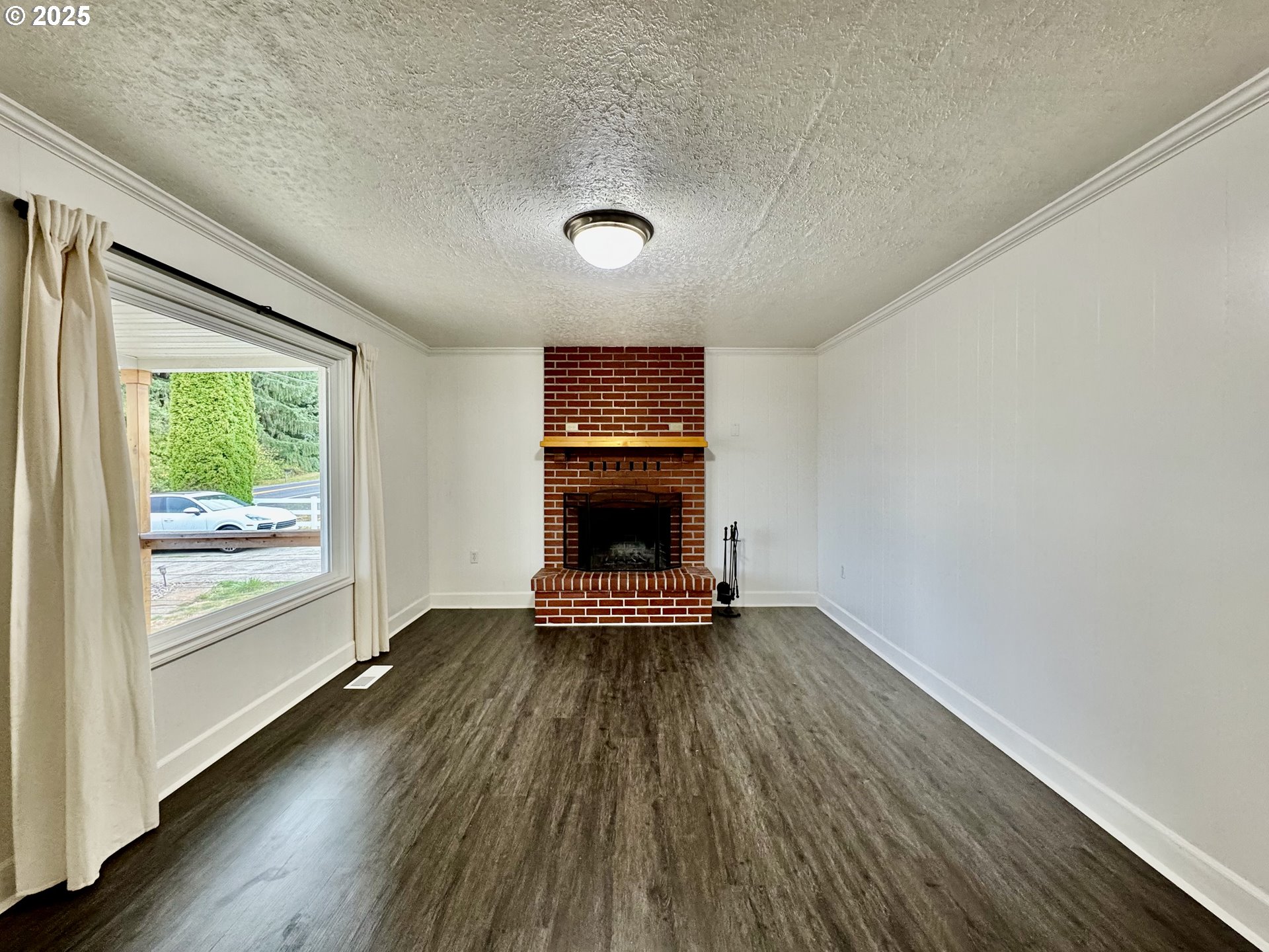 34603 Church Road Warren, OR 97053 - Photo 13 of 42 an empty room with wooden floor a fireplace and windows