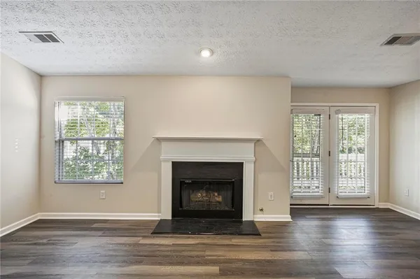 a view of an empty room with wooden floor fireplace and a window