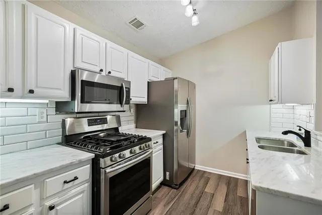 a kitchen with stainless steel appliances granite countertop a sink stove and cabinets