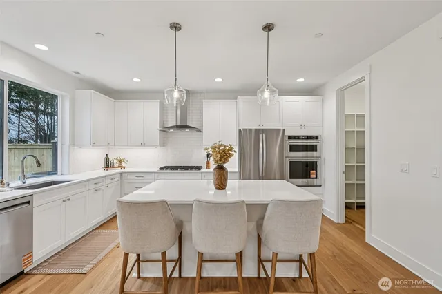 a kitchen with stainless steel appliances granite countertop a sink a stove a refrigerator and chairs