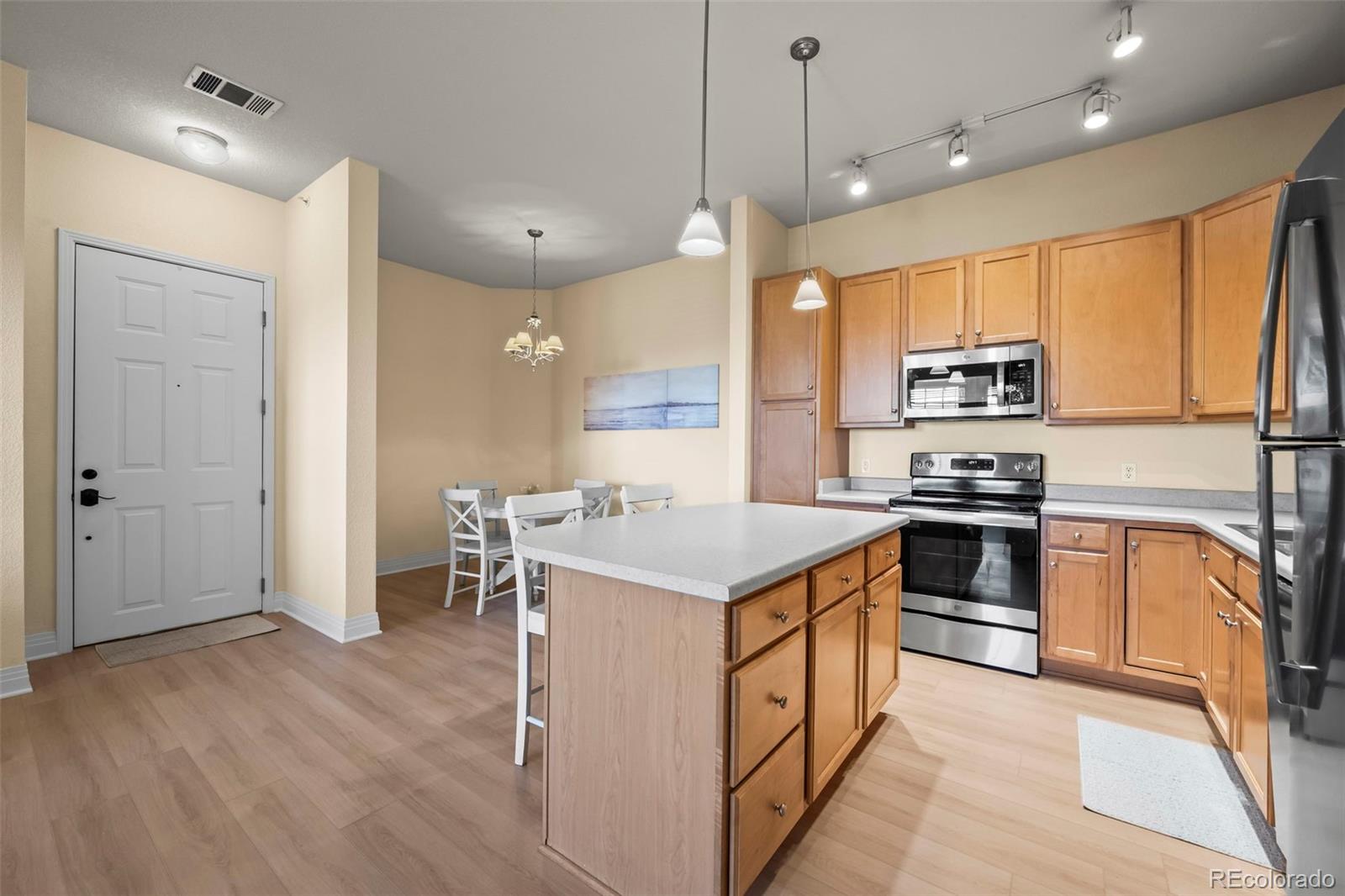 209 Quebec Street, Unit L Denver, CO 80220 - Photo 13 of 46 a kitchen with stainless steel appliances granite countertop a stove a sink a refrigerator and a dining table with wooden floor