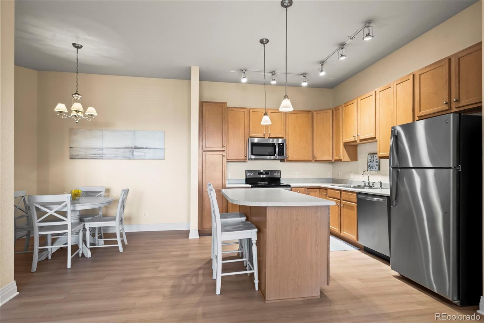 209 Quebec Street, Unit L Denver, CO 80220 - Photo 14 of 46 a kitchen with stainless steel appliances a dining table chairs refrigerator and microwave
