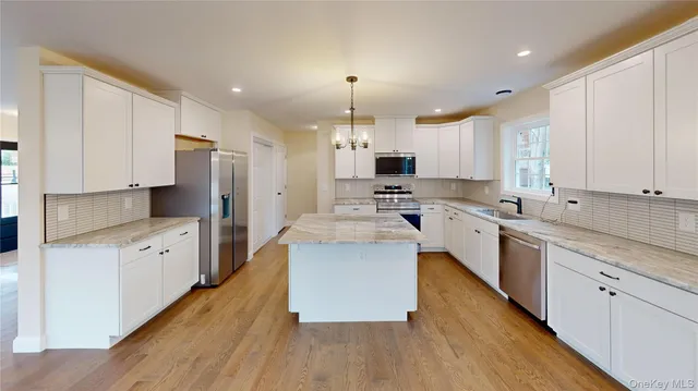 a view of an empty room and kitchen with wooden floor and a window