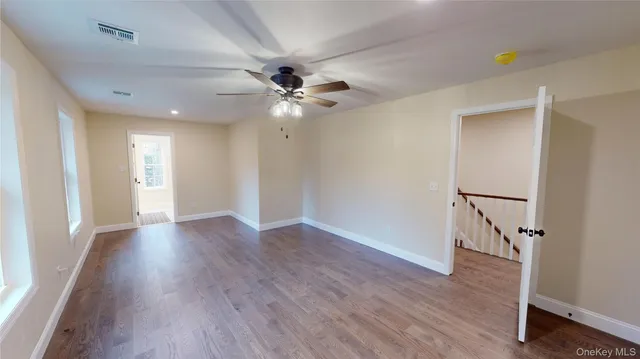 a view of an empty room with a window and wooden floor
