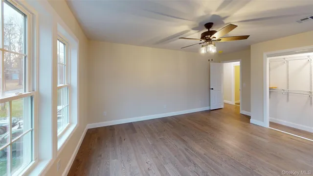 an empty room with wooden floor ceiling fan and window