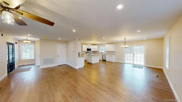 a view of an empty room and kitchen with a sink