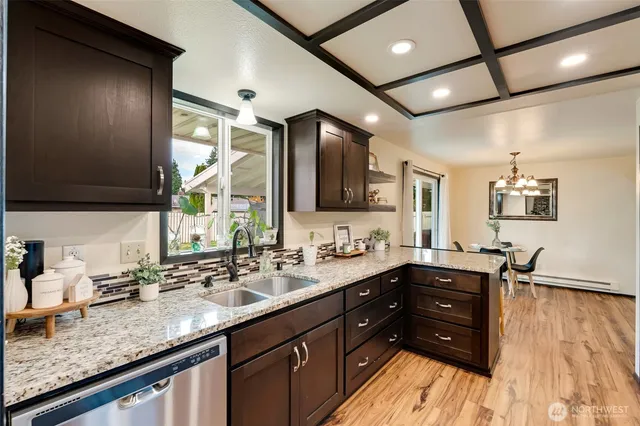a kitchen with granite countertop a sink cabinets and wooden floor