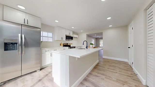 a large kitchen with stainless steel appliances a refrigerator and a stove top oven