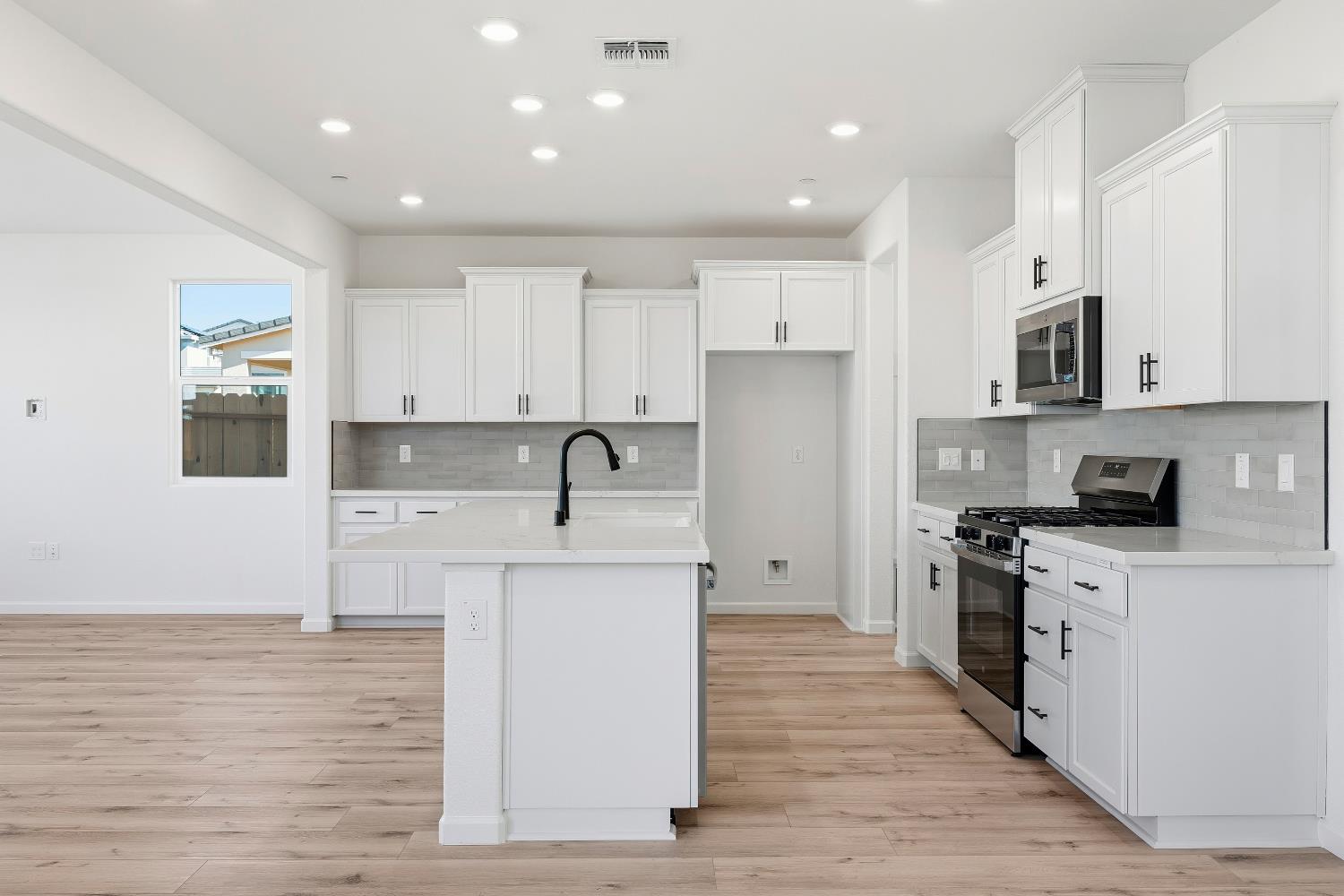 4401 Canyon Coral Way Rancho Cordova, CA 95742 - Photo 12 of 23 a kitchen with stainless steel appliances granite countertop a stove top oven a sink a refrigerator and white cabinets with wooden floor