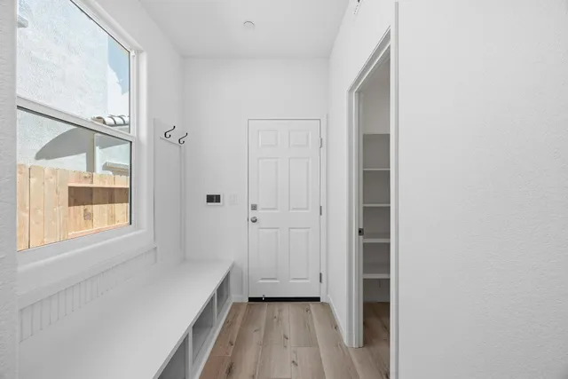 a large white kitchen with kitchen island a sink appliances wooden floor and a window