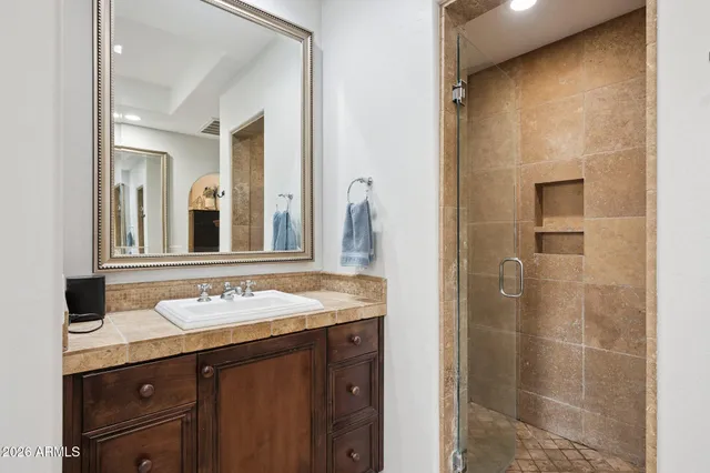 a bathroom with a granite countertop sink a mirror and a shower
