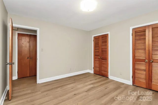 a view of an empty room with wooden floor and closet