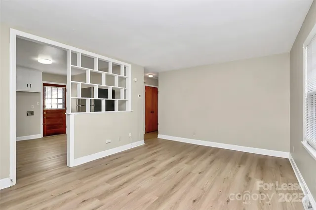a view of an empty room with wooden floor and windows