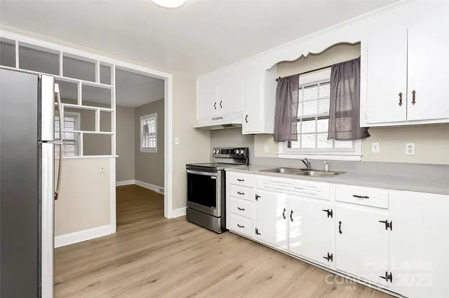 a kitchen with stainless steel appliances white cabinets and wooden floors