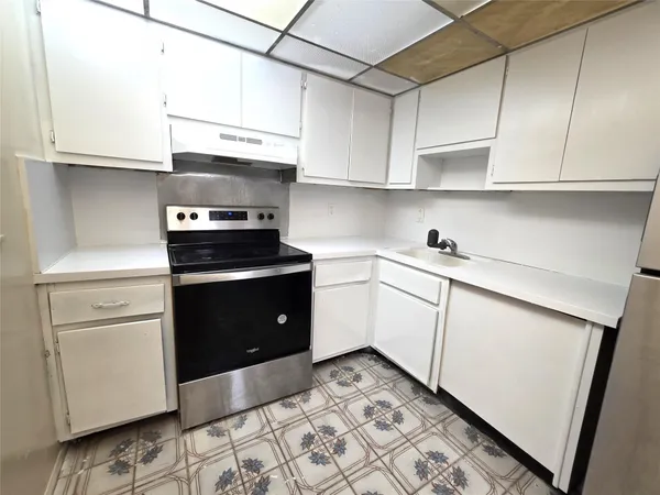 a kitchen with white cabinets and appliances
