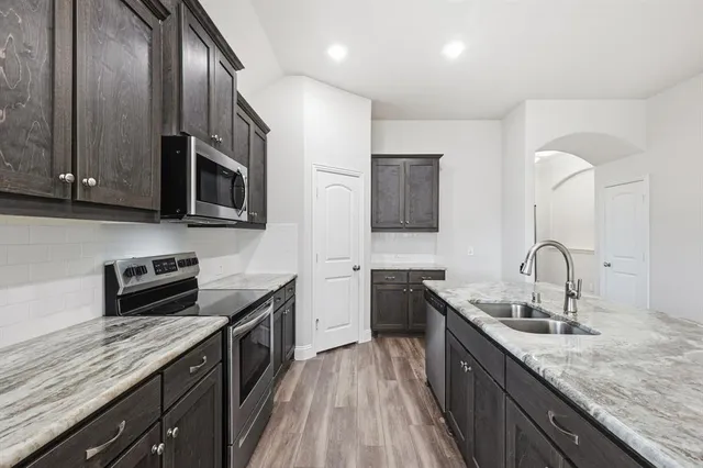 a kitchen with stainless steel appliances granite countertop a sink stove and microwave
