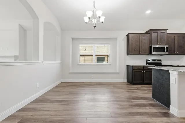 a kitchen with granite countertop a stove top oven a sink and dishwasher with wooden floor