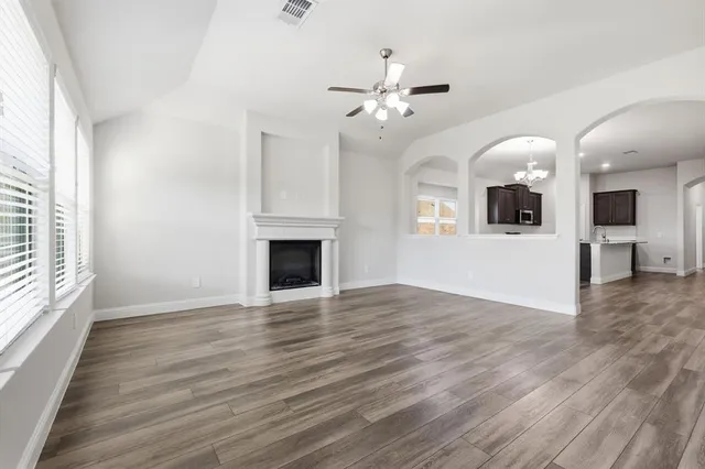 an empty room with wooden floor fan and windows