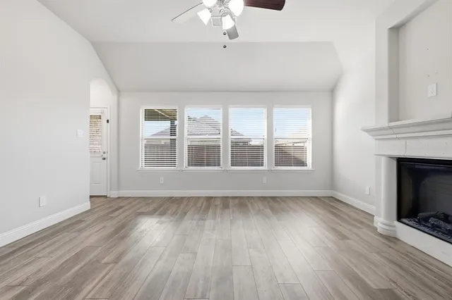 a view of an empty room with wooden floor fireplace and a window