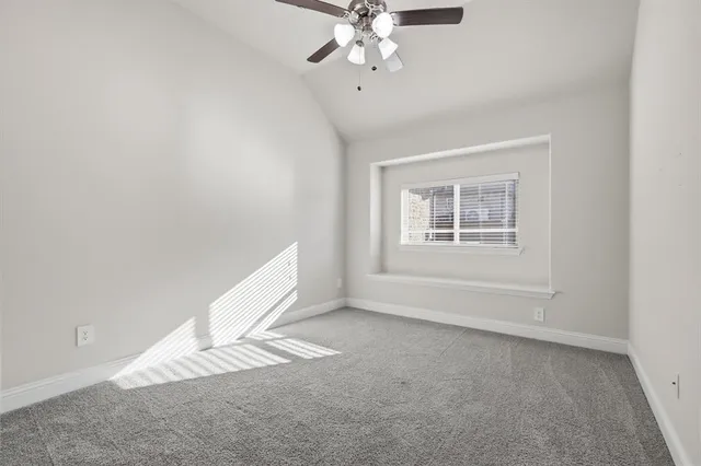 an empty room with a chandelier fan and windows