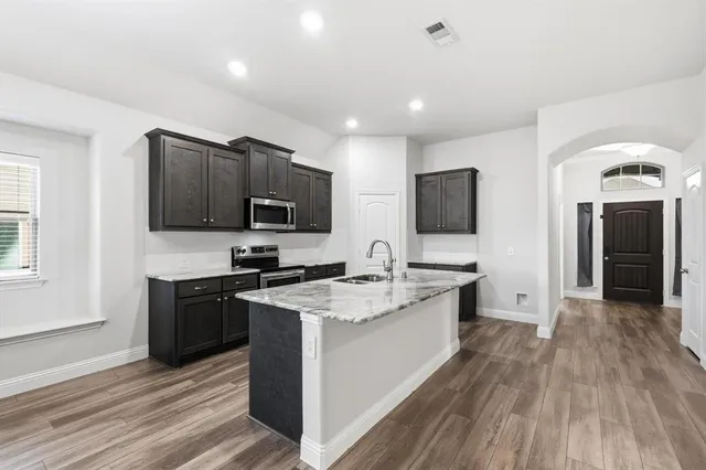 a large kitchen with stainless steel appliances granite countertop a stove and a wooden floors