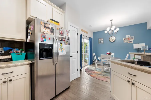 a kitchen with stainless steel appliances granite countertop a refrigerator a stove a dining table and chairs with wooden floor