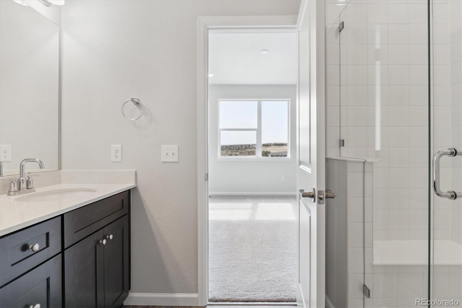 453 Interlocken Boulevard, Unit 103 Broomfield, CO 80021 - Photo 11 of 15 a bathroom with a granite countertop sink a mirror and a shower