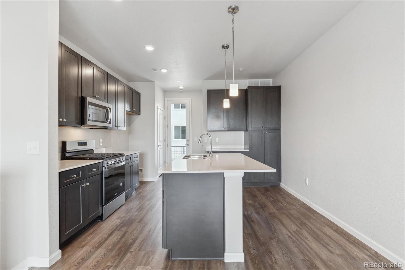 453 Interlocken Boulevard, Unit 103 Broomfield, CO 80021 - Photo 3 of 15 a large kitchen with kitchen island a sink stainless steel appliances and cabinets