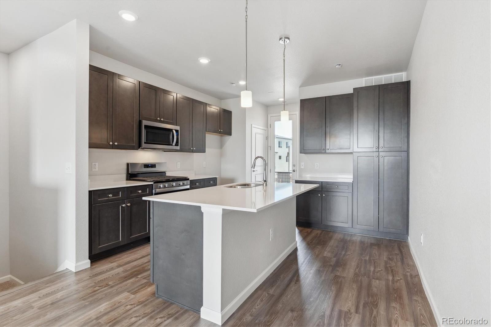 453 Interlocken Boulevard, Unit 103 Broomfield, CO 80021 - Photo 4 of 15 a kitchen with kitchen island a sink stainless steel appliances and cabinets