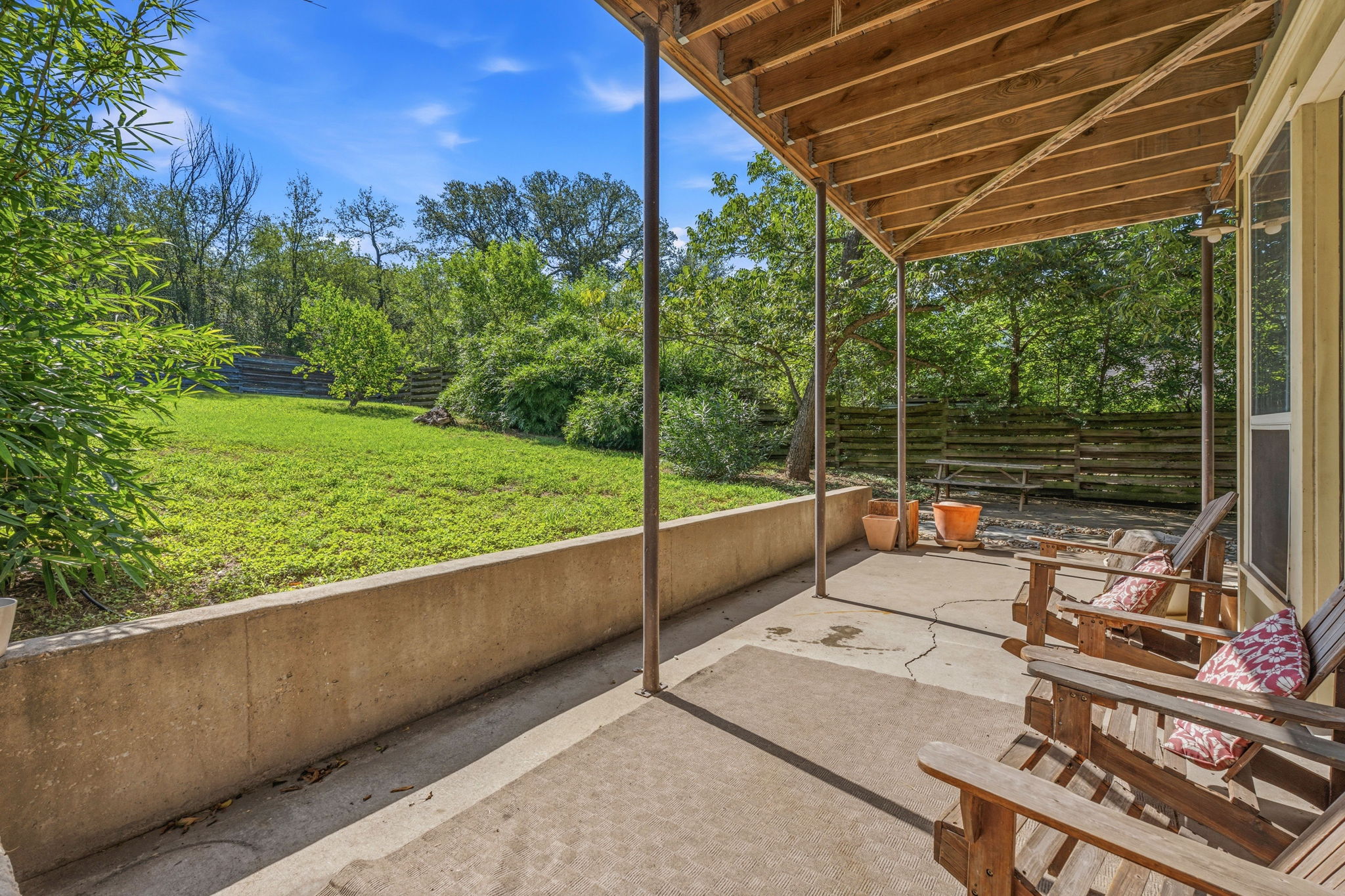 1305 Cometa Street Austin, TX 78721 - Photo 22 of 28 A spacious covered patio offers a private outdoor retreat overlooking a verdant lawn and natural landscaping.