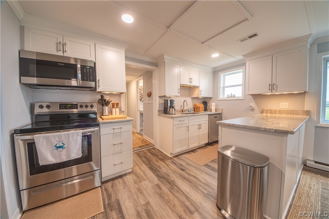 215 Riverside Drive Deltaville, VA 23043 - Photo 19 of 49 a kitchen with stainless steel appliances white cabinets a sink a stove a microwave and wooden floors