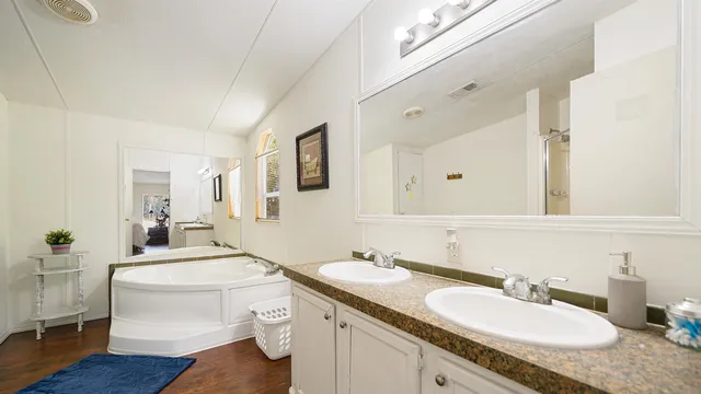 a en suite bathroom with a granite countertop double vanity sink a mirror and a toilet