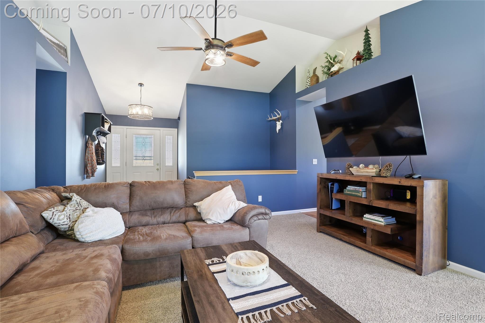 5275 East Maple Avenue Grand Blanc, MI 48439 - Photo 13 of 53 Living area featuring vaulted ceilings, a ceiling fan with integrated lighting, and carpet flooring