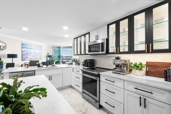 a kitchen with stainless steel appliances a sink a stove a refrigerator cabinets and a window