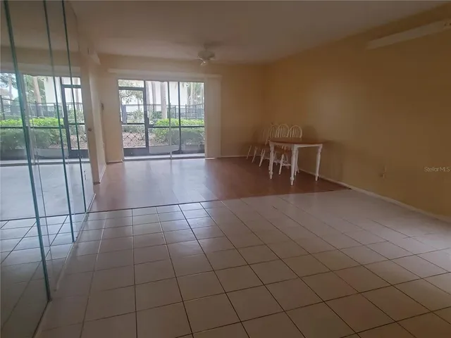 an empty room with floor to ceiling window and ceiling fan